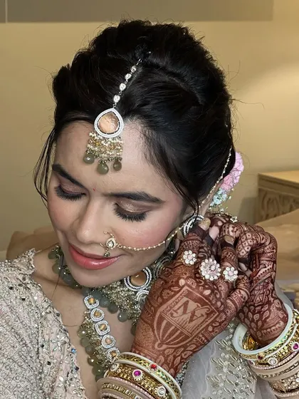 A beautiful bride getting ready, her hair styled in a textured updo with pink carnations.