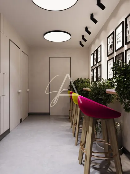 A casual breakout area within a corporate office. The vibrant pink and yellow bar stools add a playful pop of color to the neutral space, providing a spot for informal discussions or a quick coffee break.