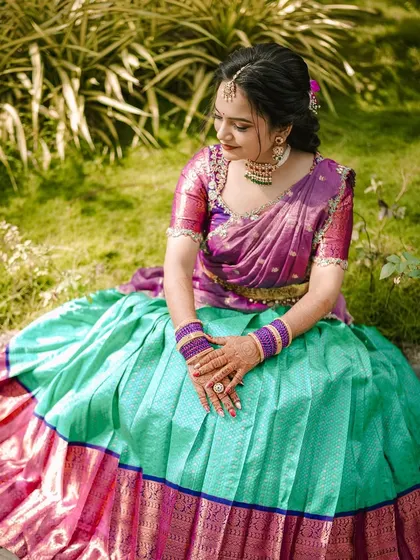 Rashmika's engagement look. The vibrant purple and turquoise half-saree is so eye-catching, and the makeup is kept soft and pretty to balance the look.