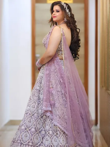 A back view of the bride, showcasing her long, flowing curls and the beautiful backless design of her lavender gown.