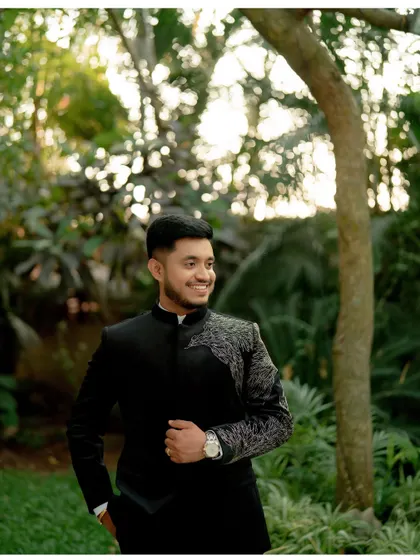 A handsome portrait of the groom, Akshay, looking sharp in his reception attire amidst the lush greenery of The Peacock Grove.