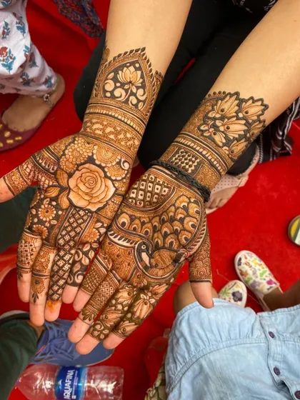 This design is a beautiful mix of floral and peacock motifs. A large rose is the centerpiece on one palm, while a peacock adorns the other, both surrounded by dense, detailed patterns.