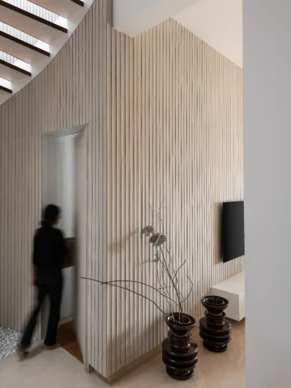 A camouflaged door is concealed within the fluted wood wall, a playful detail that maintains the clean, uninterrupted lines of the contemporary design.