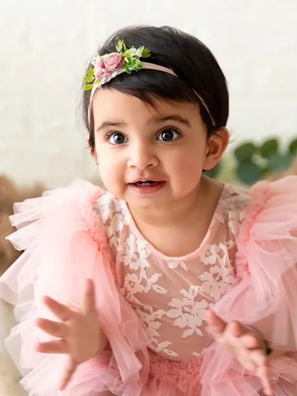 A close-up portrait capturing the baby's bright eyes and sweet expression during her first birthday photoshoot.
