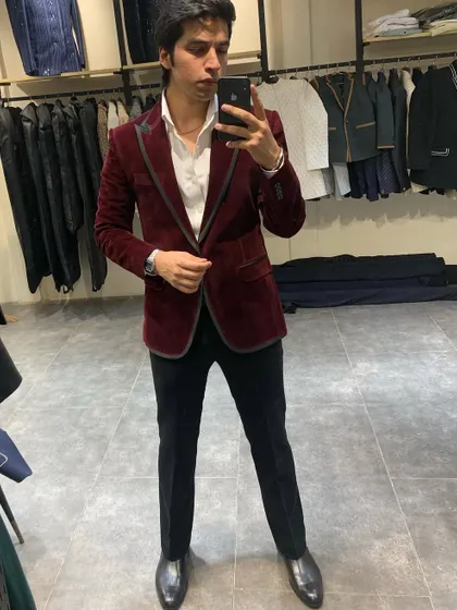 A full-length mirror shot capturing the complete maroon velvet blazer outfit. The sharp cut and luxurious fabric create an effortlessly polished and confident appearance.