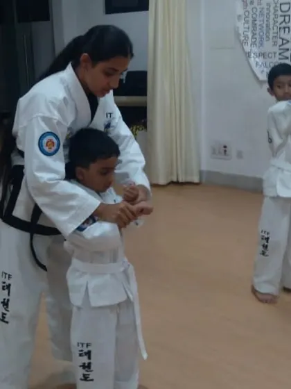 A female instructor provides hands-on correction to a young student, ensuring proper form from the very beginning.