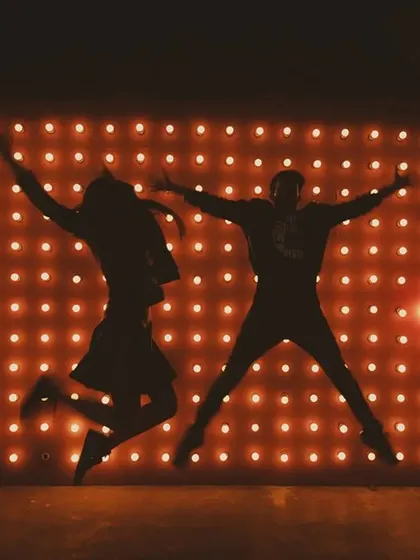 A fun and energetic silhouette of a couple jumping for joy against a wall of lights, capturing their excitement.