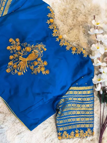 A complete view of the blue blouse with a peacock motif, showcasing how the design flows from the back to the sleeves.