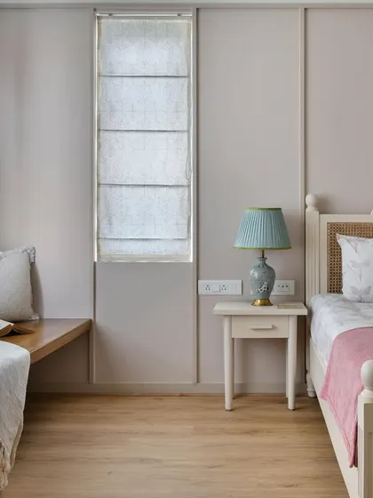 A cozy corner in the French-inspired bedroom from 'House of Kismish', showing a window seat with a soft throw blanket. The paneled walls and pastel tones add to the room's delicate charm.