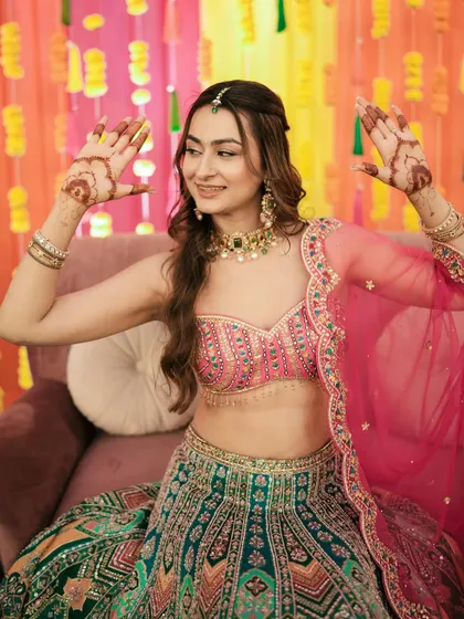 The bride playfully shows off her mehndi-adorned hands during the Sangeet ceremony.