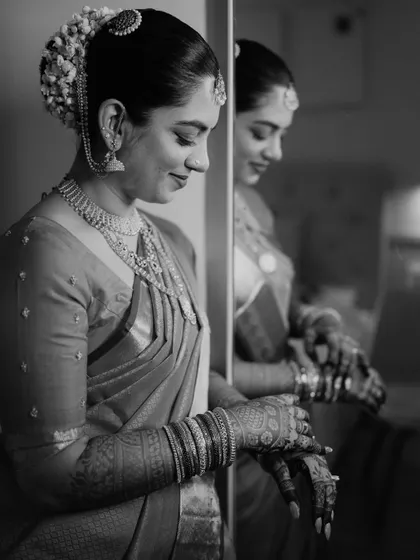 A contemplative black and white portrait. The reflection adds depth, and the focus is on the bride's serene expression and the timeless quality of her look.