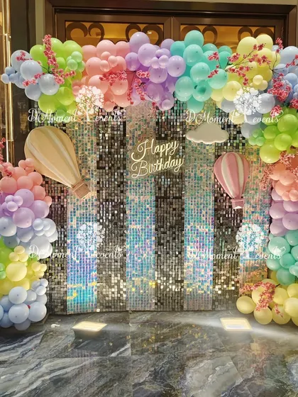 A beautiful photo backdrop with a sequin wall, pastel balloon arch, and hot air balloon accents, perfect for capturing sweet party moments.