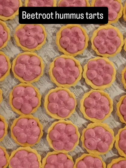 Beetroot hummus tarts sit in rows on our catering tray, with the pink filling piped into each pastry shell.