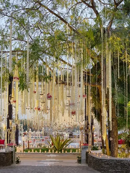 A daytime event in Udaipur featuring thousands of suspended floral strings, creating a magical, swaying canopy over the guest seating and bar areas.