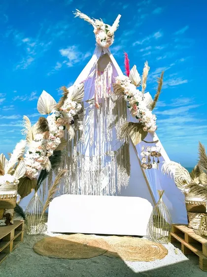 The stunning teepee-style photo booth for the Boho beach lunch, decorated with macrame, pampas grass, and seashells.