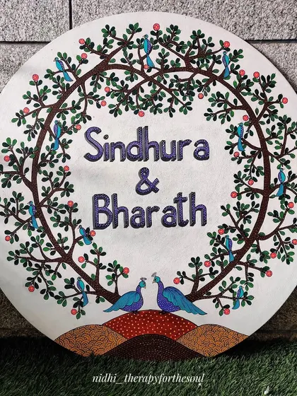 A beautiful Gond art name board I created for a wedding. The circular canvas is framed by the tree of life, with two peacocks at the bottom symbolizing the couple, Sindhura and Bharath.