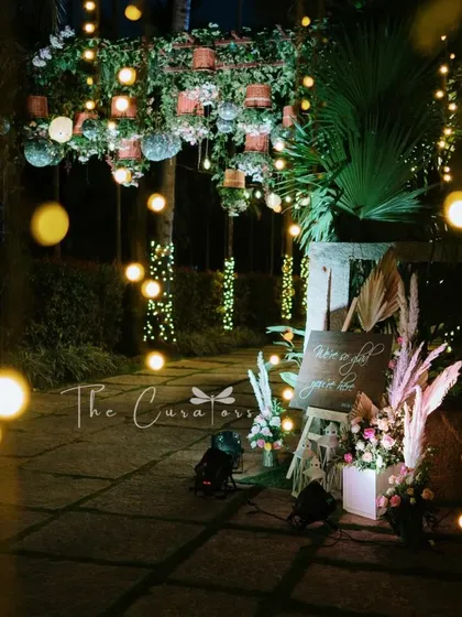 A welcome sign and floral arrangement greet guests at the start of the fairy-lit path, setting a warm and inviting tone for the reception.