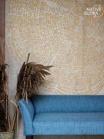 The entrance foyer of Villa Tranquility, where a vibrant blue sofa is set against the spiritually significant, gold-inlaid carved marble wall. Dried reeds in a tall vase add a natural, grounding touch.