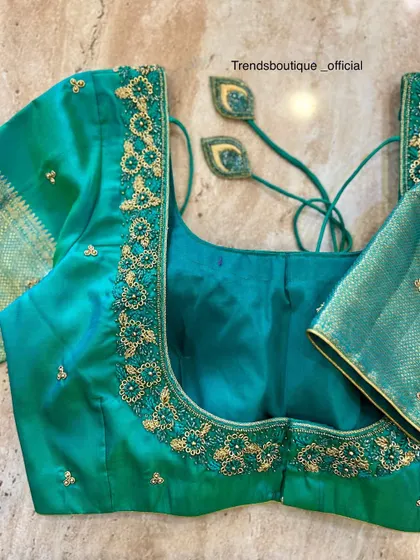 A full view of the teal green blouse, showing the zardosi work on both the front and back neckline, along with matching tassels.