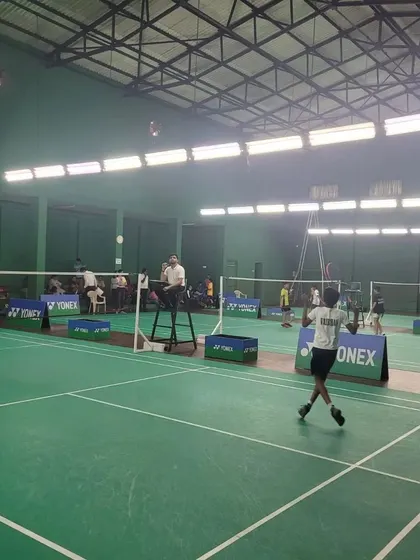Another angle of a player serving during the tournament, with spectators watching in the background.