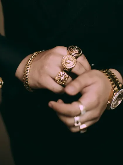 A tightly framed shot of the groom's hands, emphasizing the texture and shine of his gold jewelry. These kinds of detail shots add a layer of richness and personality to the wedding album.