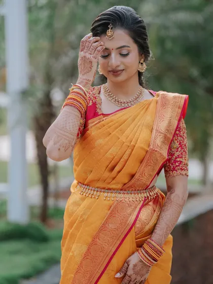 Adjusting her jewellery, this bride is a picture of traditional elegance. The makeup is designed to be radiant and long-lasting, perfect for the day's ceremonies.