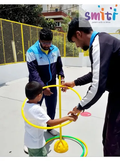 A coach helps a child with a hula hoop activity. Our sports sessions are led by trained professionals who make learning skills enjoyable.