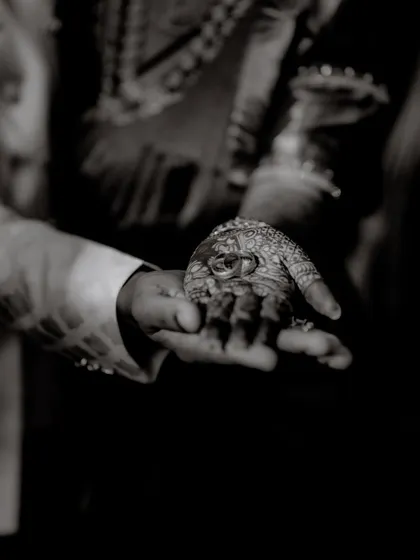 A dramatic black and white shot of the wedding rings resting in the groom's hand. This artistic photo emphasizes the sanctity and importance of the rings as symbols of commitment.