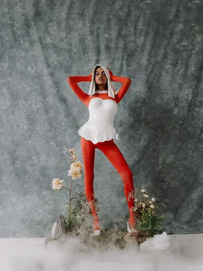 A standing pose from the red and white conceptual shoot, emphasizing the sculptural quality of the custom breastplate.