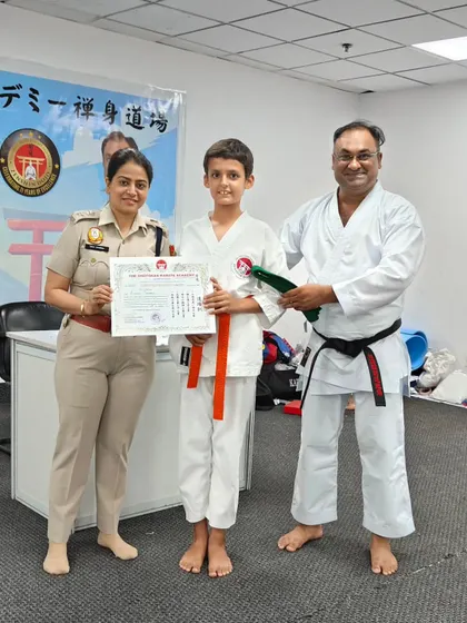 Awarding an orange belt to a dedicated young student. The colored belt system provides clear goals and a visual representation of a student's progress in their karate training.