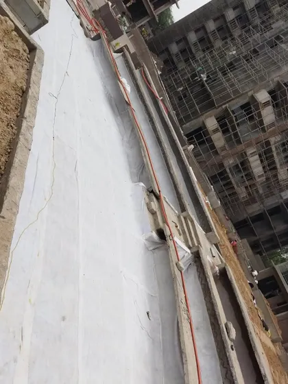 After the drainage cells, we lay down a geotextile filter fabric. This white sheet prevents soil from clogging the drainage system while allowing water to pass through freely.