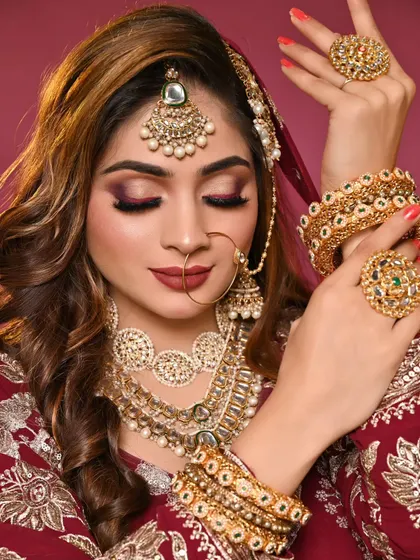 A stunning bridal look in a deep maroon peplum lehenga. The smokey eye makeup is dramatic yet elegant, perfect for a winter wedding.