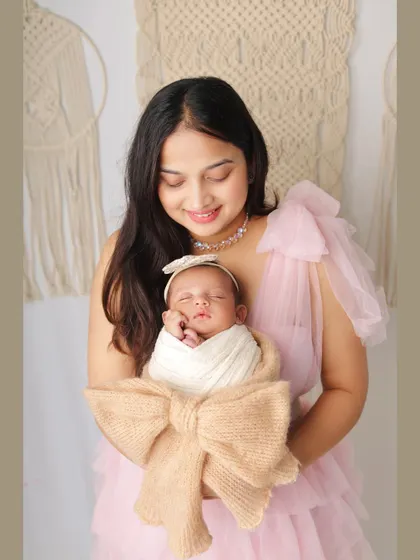 A mother's love shines in this portrait. She holds her swaddled newborn close, creating a memory of those precious early days.