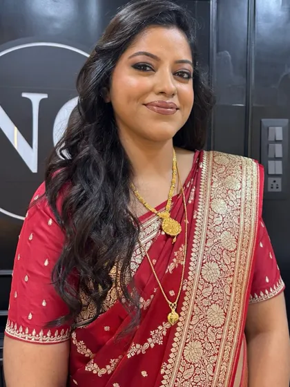 Radiance redefined for a wedding guest. This flawless dewy makeup with a soft smokey eye and nude lip is a timeless choice that looks graceful with her red saree.