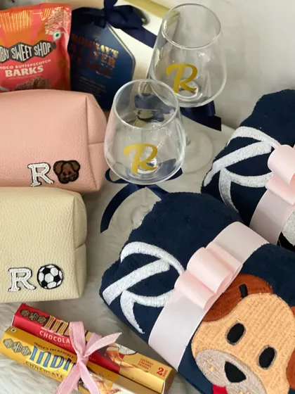A close-up of the personalized details from the football and animal lover's hamper. The custom embroidered pouches and towels with a soccer ball and a dog icon add such a unique and personal touch.