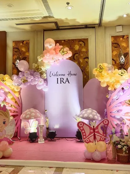 A "Welcome Home IRA" party with a pink butterfly theme, featuring large wing props and a fairy character cutout.