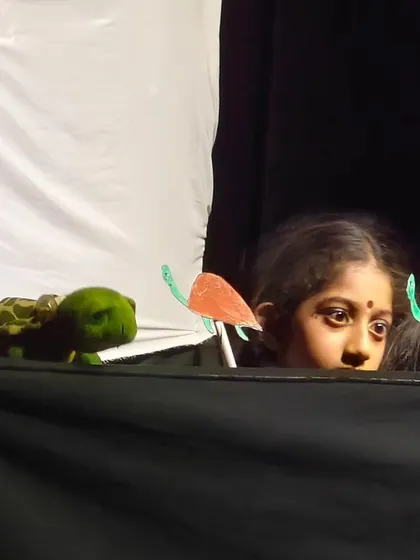 A peek behind the curtain of a children's puppet show, showing the focus and imagination of the young puppeteer.