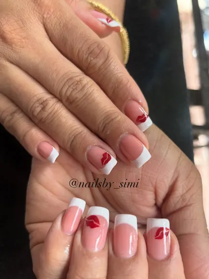 A classic French manicure with a playful twist. This design features a crisp white tip on a square nail shape, with a cute red kiss print accent on a few nails.