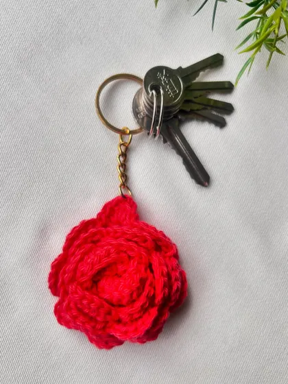 A bright red rose keychain attached to a set of keys, showing how practical and pretty it is.