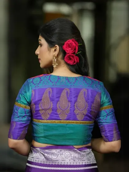 A stunning dual-tone blouse in teal and purple, featuring a traditional paisley motif on the back. The rich silk fabric makes it perfect for festive occasions.