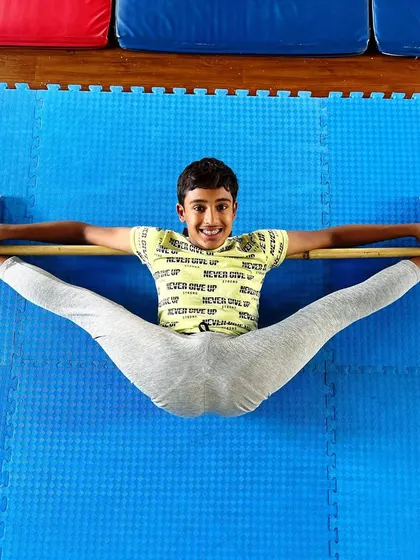 Flexin' on 'em with style. This young athlete shows off his impressive middle split using a stick for support, a great tool for achieving proper alignment.