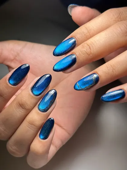 Another angle showcasing the deep blue cat-eye nails with a subtle silver accent. We teach you how to add small details that complement and enhance a bold design.