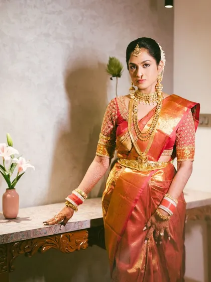 An elegant, full-length portrait of a South Indian bride in her magnificent Kanjeevaram saree. This shot showcases the beauty and grace of traditional bridal attire.