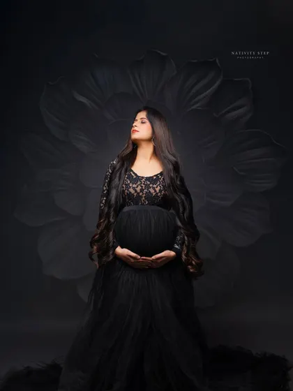 A powerful and elegant solo portrait. We use dramatic studio lighting and a classic black gown to sculpt the beautiful silhouette of the baby bump, creating a timeless piece of art.