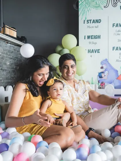 A happy family photo in the ball pit at Roohi's Jungle Book party. The personalized milestone board in the background adds a lovely, sentimental touch.