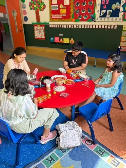 Students gather around the table to assemble their own bhel puri. This activity not only teaches culinary skills but also encourages social interaction and teamwork as they share ingredients and ideas.
