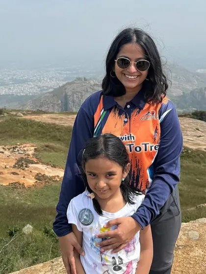 A mother and her young daughter on a 'Mom & Me' trek, with a vast landscape behind them. These hikes are designed to be accessible and enjoyable for young children.