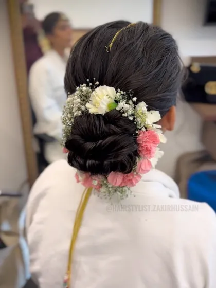 This full floral bun combines pink and white carnations with baby's breath for a lush, multi-dimensional look. It’s a statement hairstyle that is both romantic and traditional, perfect for a grand wedding.