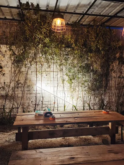 At night, simple wall lighting behind a screen of bamboo creates a dramatic and stylish backdrop for this cafe's outdoor seating area.