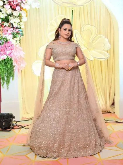 A client looking confident and stylish in the champagne gold lehenga at an event.